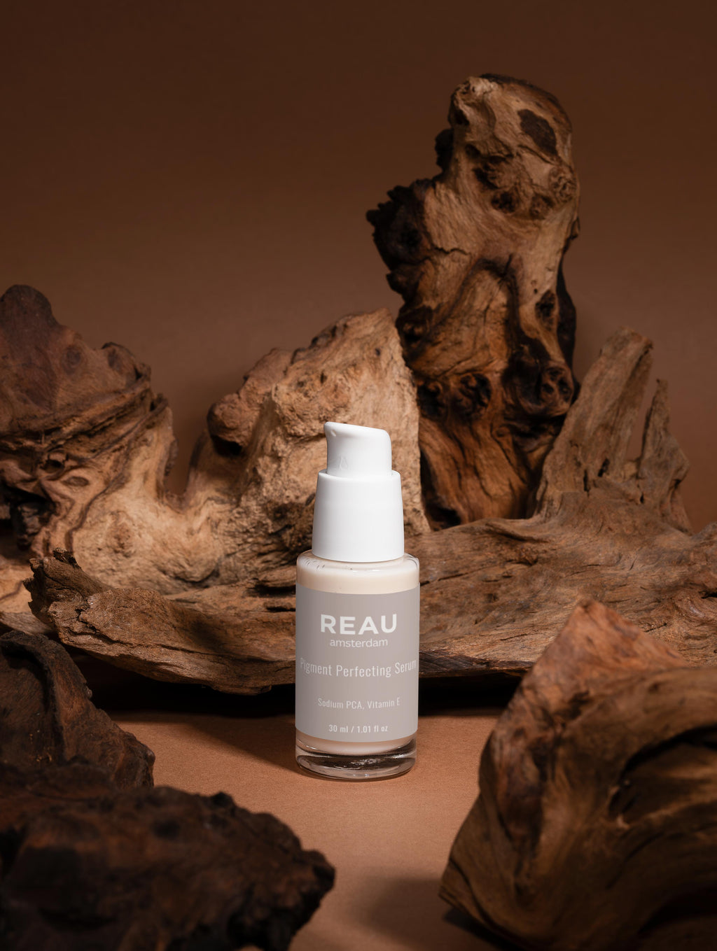 REAU skincare bottle on a brown background with natural wood elements