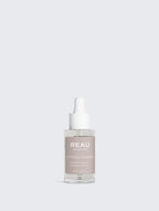 Skincare serum bottle with 'REAU' branding on a light gray background